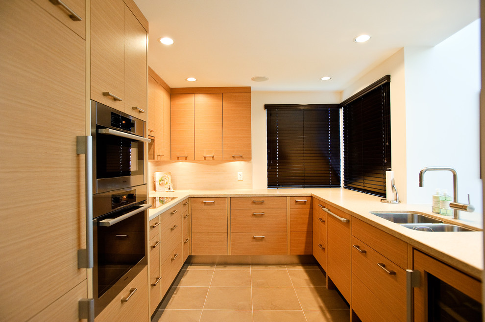 This is an example of a contemporary u-shaped kitchen in Vancouver with integrated appliances, a double-bowl sink, flat-panel cabinets and medium wood cabinets.