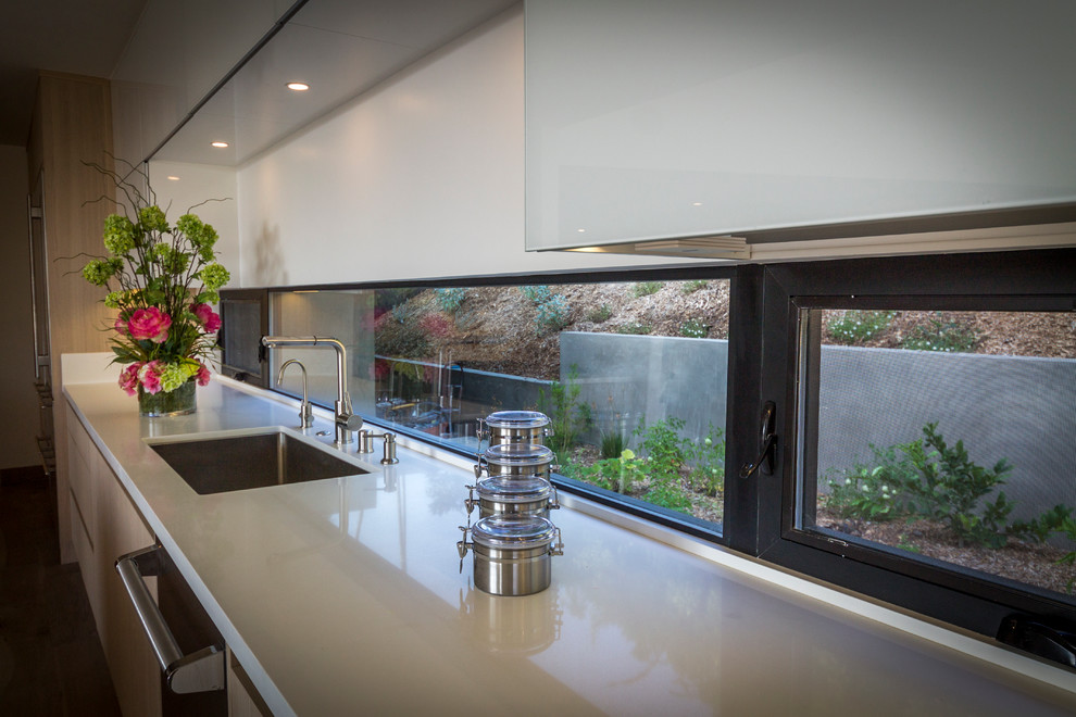 Esempio di una grande cucina minimalista con lavello integrato, ante lisce, ante in legno chiaro, top in laminato, elettrodomestici in acciaio inossidabile e pavimento in legno massello medio