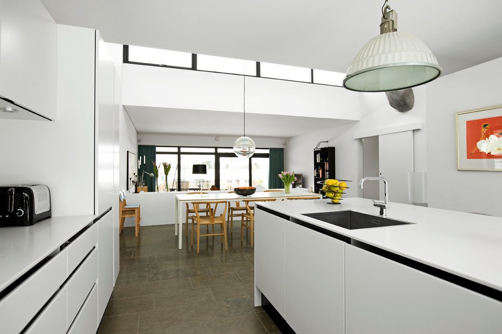 Стильный дизайн: большая кухня в современном стиле с плоскими фасадами, белыми фасадами, островом и коричневым полом - последний тренд