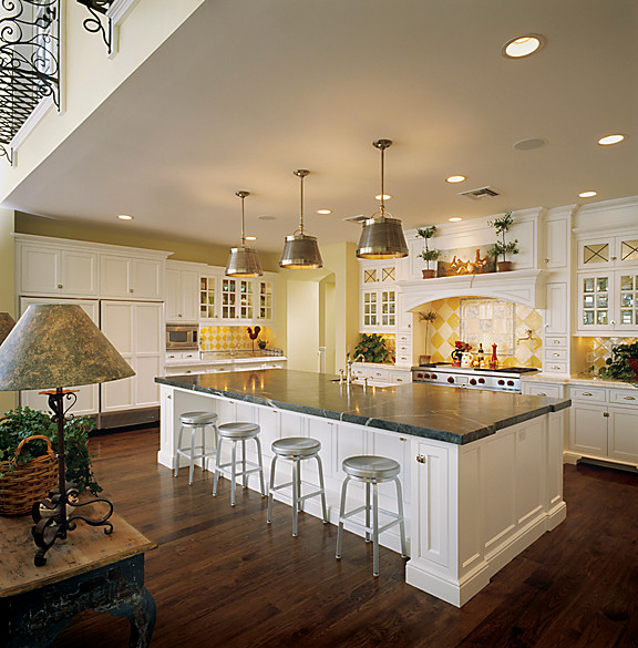 Inredning av ett klassiskt stort kök, med luckor med infälld panel, vita skåp, marmorbänkskiva, gult stänkskydd, stänkskydd i keramik, rostfria vitvaror, mellanmörkt trägolv och en köksö