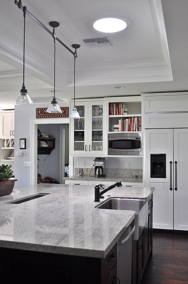 Aménagement d'une cuisine encastrable classique avec un placard à porte shaker, un évier de ferme, des portes de placard blanches et un plan de travail en granite.
