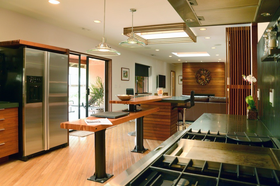 Exemple d'une cuisine ouverte tendance en U et bois foncé de taille moyenne avec un évier encastré, un placard à porte plane, un électroménager en acier inoxydable et un sol en bois brun.