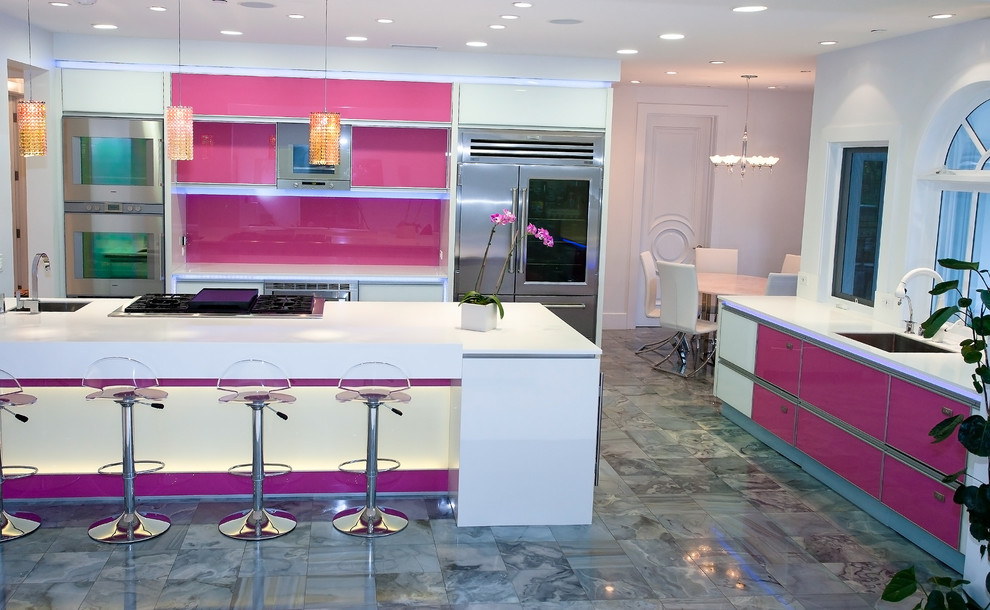 Modern inredning av ett kök och matrum, med rostfria vitvaror, en enkel diskho, släta luckor, rosa stänkskydd och glaspanel som stänkskydd