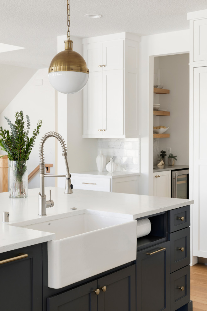 Bild på ett vintage kök, med vita skåp, bänkskiva i kvartsit, stänkskydd i marmor, rostfria vitvaror, ljust trägolv och en köksö