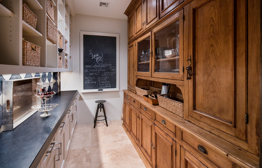 Diseño de cocina clásica con despensa, armarios con paneles empotrados, puertas de armario de madera oscura, salpicadero blanco, suelo beige y encimeras grises