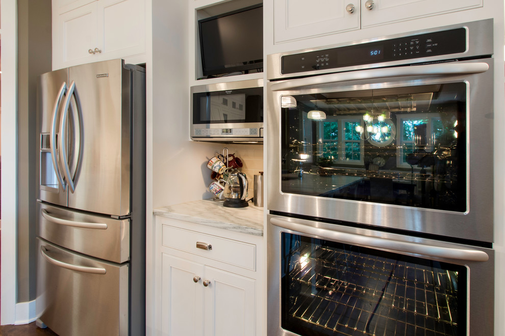 Photo of a large classic kitchen/diner in Minneapolis with flat-panel cabinets, white cabinets, white splashback, stainless steel appliances, medium hardwood flooring and an island.