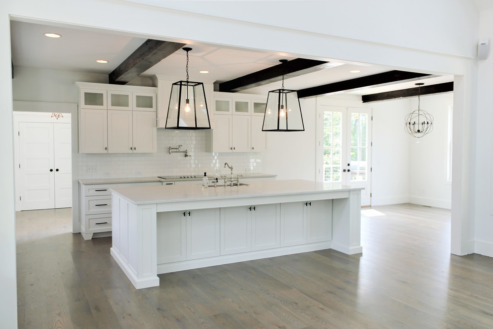 Lantlig inredning av ett mellanstort kök och matrum, med luckor med infälld panel, vita skåp, marmorbänkskiva och en köksö