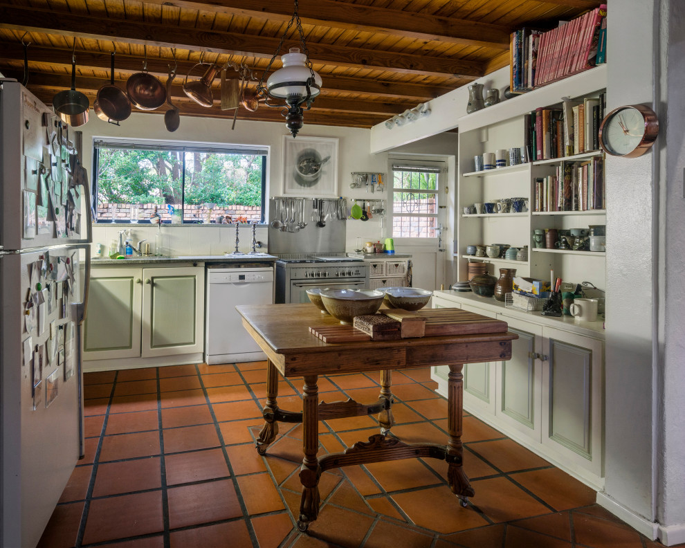 Country u-shaped kitchen in Other with raised-panel cabinets, green cabinets, an island, brown floors, grey worktops, exposed beams and a wood ceiling.
