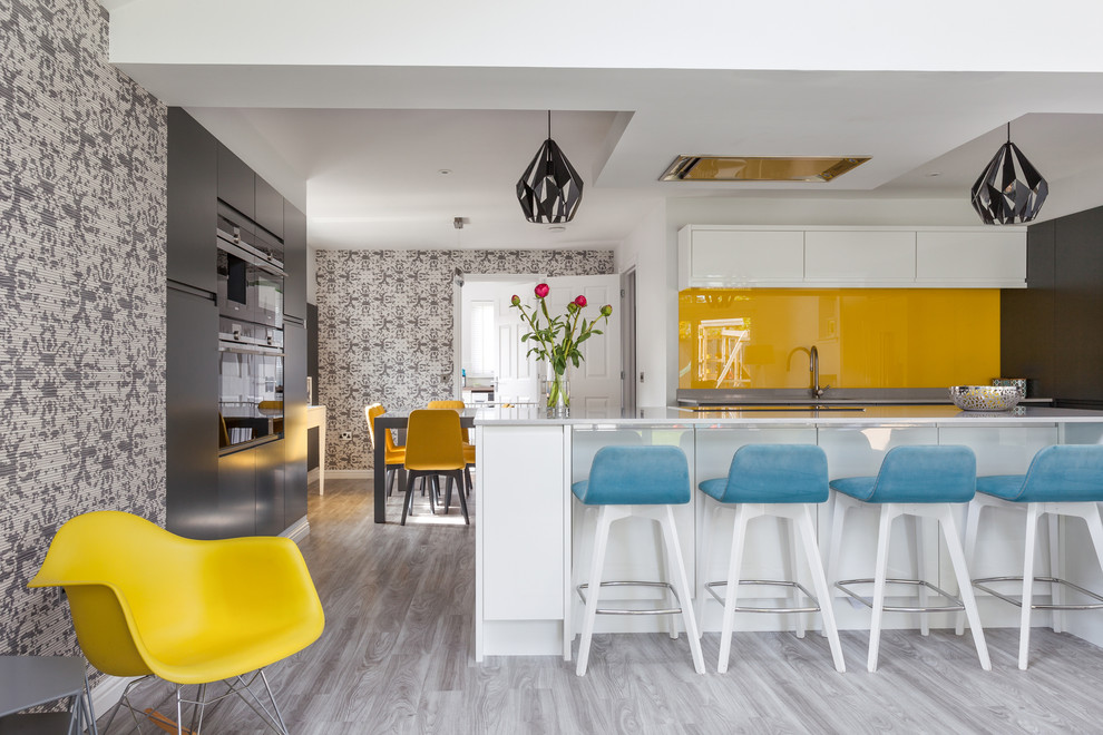 Moderne Wohnküche in U-Form mit flächenbündigen Schrankfronten, weißen Schränken, Küchenrückwand in Orange, Glasrückwand, Halbinsel und grauem Boden in Sonstige
