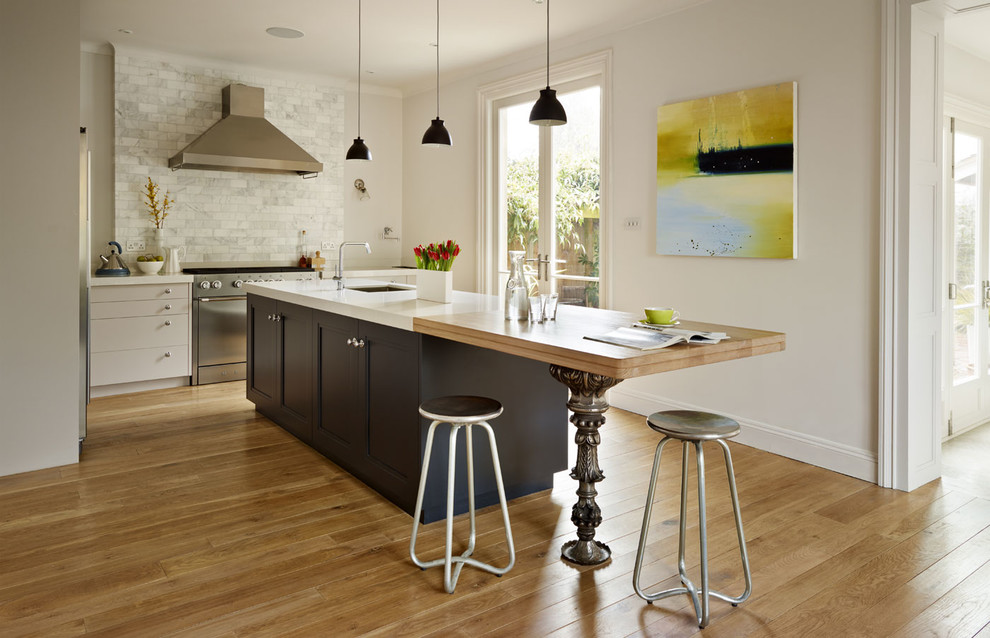 Inspiration för ett mellanstort eklektiskt l-kök, med luckor med infälld panel, vitt stänkskydd, stänkskydd i marmor, rostfria vitvaror, ljust trägolv, en köksö, svarta skåp, träbänkskiva och brunt golv