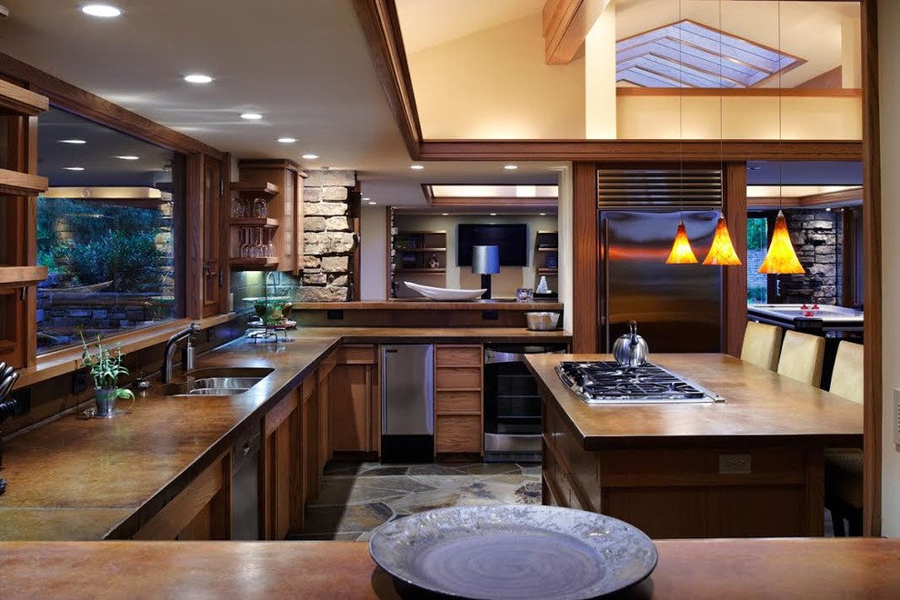 Immagine di una grande cucina contemporanea con ante in legno scuro, elettrodomestici in acciaio inossidabile, lavello sottopiano, top in cemento, paraspruzzi marrone e ante lisce