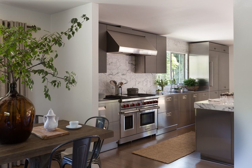 Foto på ett mellanstort funkis vit linjärt kök och matrum, med en integrerad diskho, släta luckor, skåp i rostfritt stål, marmorbänkskiva, vitt stänkskydd, stänkskydd i marmor, rostfria vitvaror, mellanmörkt trägolv och en köksö