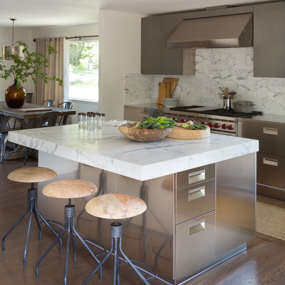 Idéer för att renovera ett mellanstort funkis vit linjärt vitt kök och matrum, med en integrerad diskho, släta luckor, skåp i rostfritt stål, marmorbänkskiva, vitt stänkskydd, stänkskydd i marmor, rostfria vitvaror, mellanmörkt trägolv och en köksö