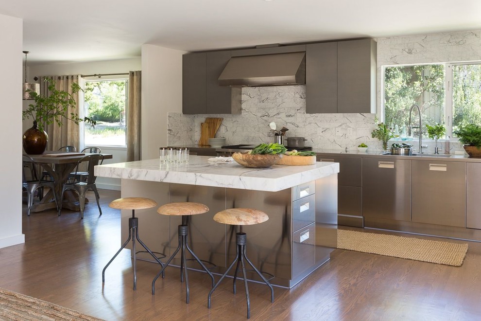Idéer för ett mellanstort modernt vit linjärt kök och matrum, med en integrerad diskho, släta luckor, skåp i rostfritt stål, marmorbänkskiva, vitt stänkskydd, stänkskydd i marmor, rostfria vitvaror, mellanmörkt trägolv och en köksö