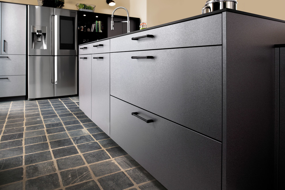 Large urban single-wall open plan kitchen in Surrey with a single-bowl sink, flat-panel cabinets, laminate countertops, black appliances, slate flooring, an island, black floors and black worktops.
