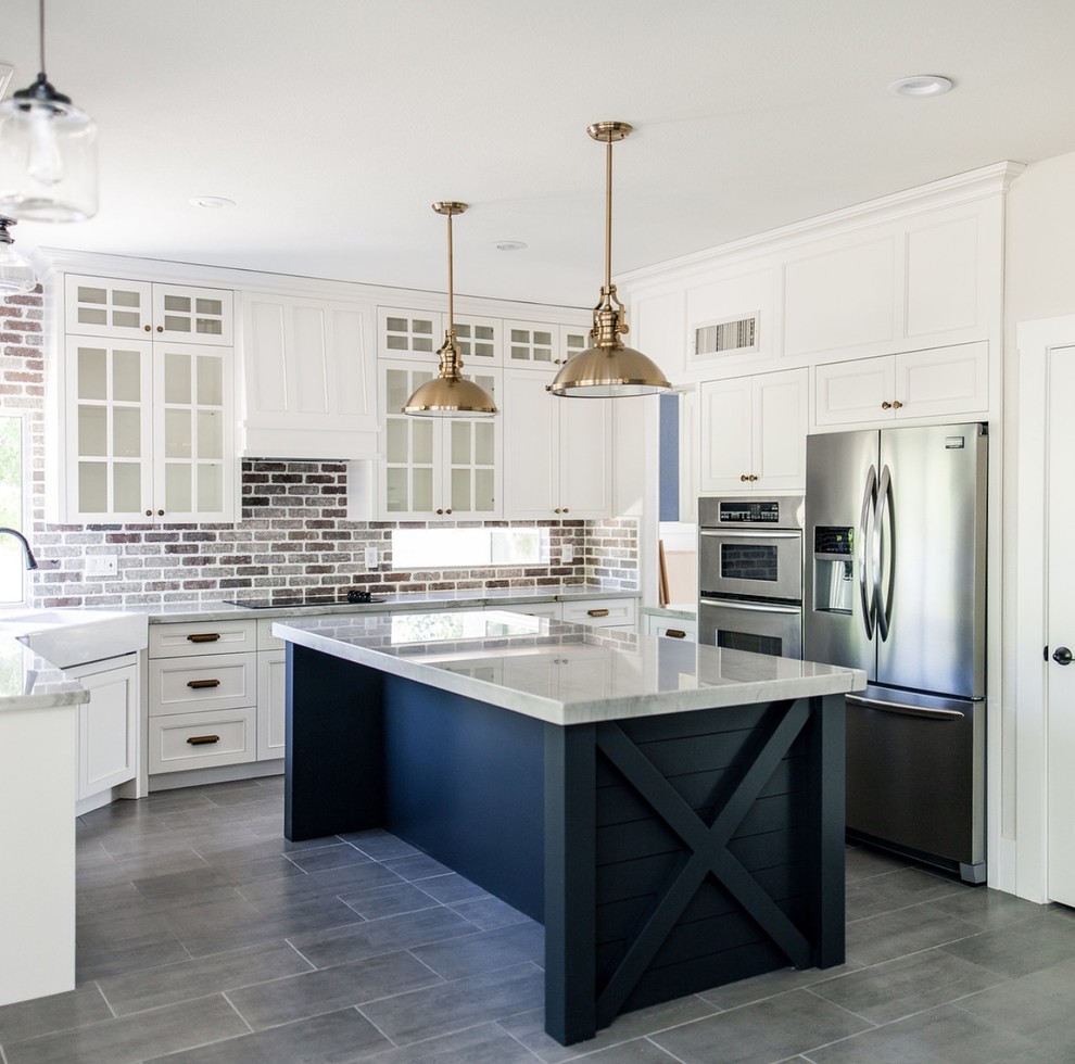 Bild på ett mellanstort lantligt vit vitt kök, med en rustik diskho, skåp i shakerstil, vita skåp, bänkskiva i kvartsit, grått stänkskydd, stänkskydd i tegel, rostfria vitvaror, klinkergolv i keramik, en köksö och grått golv