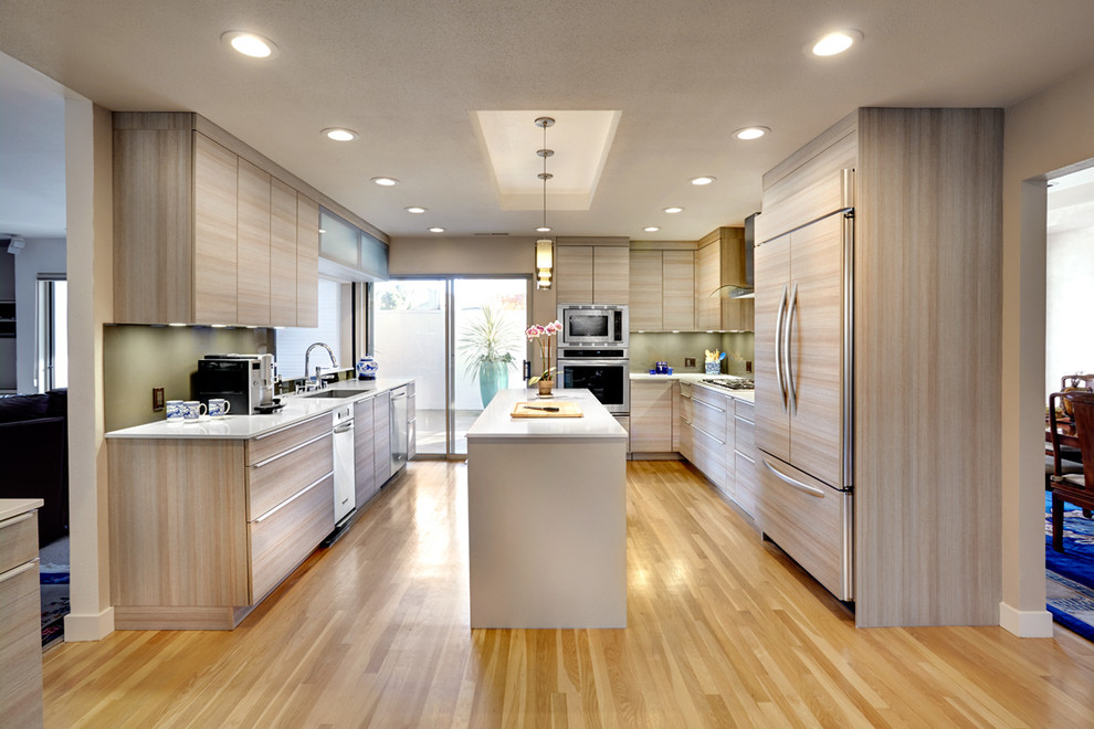 Moderne Küche in U-Form mit Unterbauwaschbecken, flächenbündigen Schrankfronten, hellen Holzschränken und Elektrogeräten mit Frontblende in Sacramento