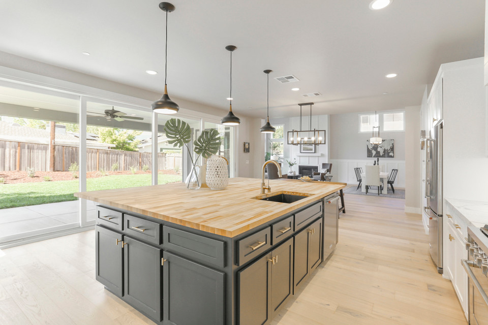 Inspiration for a large country l-shaped light wood floor and white floor eat-in kitchen remodel in Sacramento with a drop-in sink, shaker cabinets, white cabinets, quartz countertops, white backsplash, ceramic backsplash, stainless steel appliances, an island and white countertops