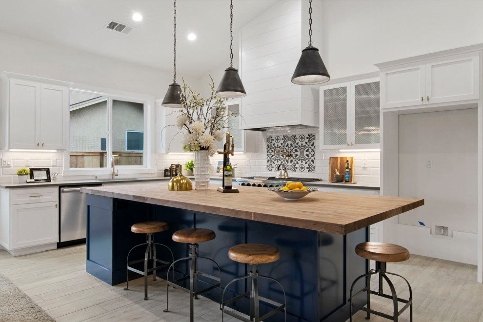 Inspiration for a large farmhouse l-shaped ceramic tile, beige floor and vaulted ceiling open concept kitchen remodel in Sacramento with an undermount sink, shaker cabinets, blue cabinets, wood countertops, white backsplash, ceramic backsplash, stainless steel appliances, an island and brown countertops
