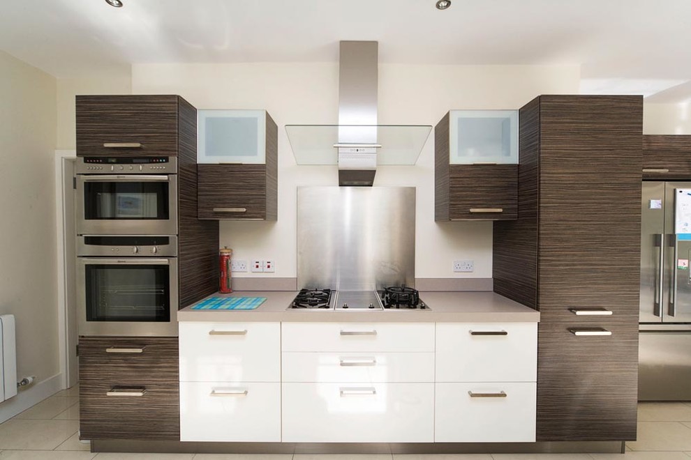 Modern inredning av ett stort kök, med en nedsänkt diskho, släta luckor, vita skåp, laminatbänkskiva, rostfria vitvaror, klinkergolv i porslin och en halv köksö