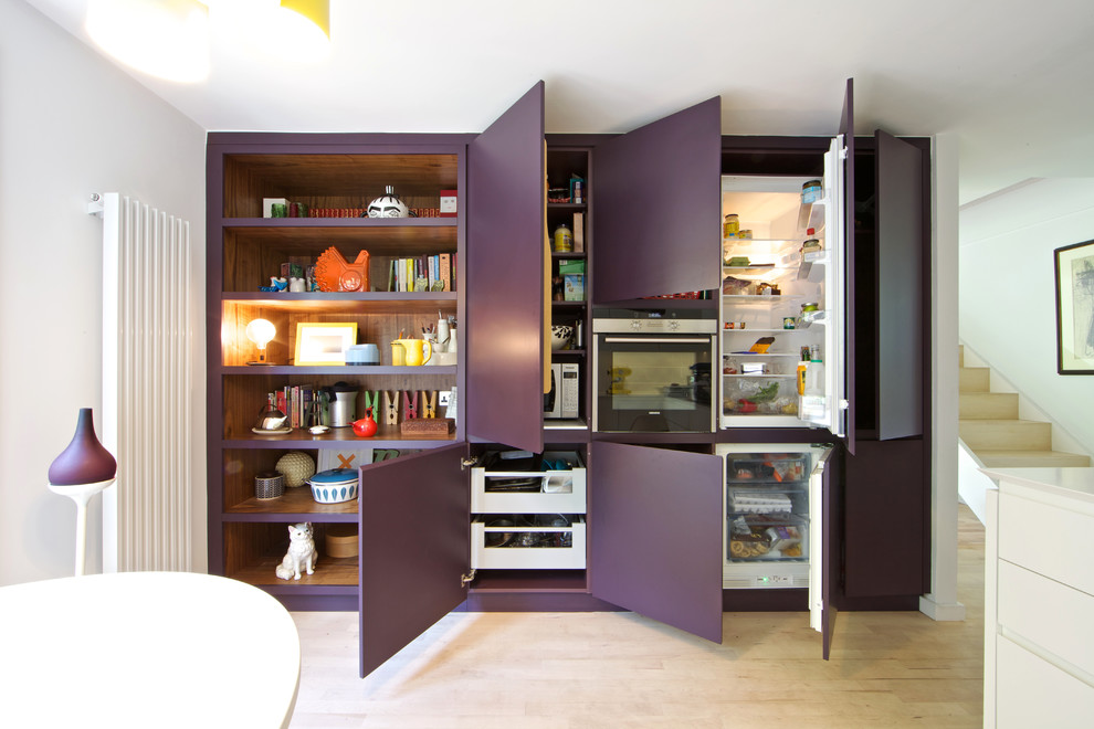Moderne Wohnküche mit flächenbündigen Schrankfronten, weißen Schränken und hellem Holzboden in London