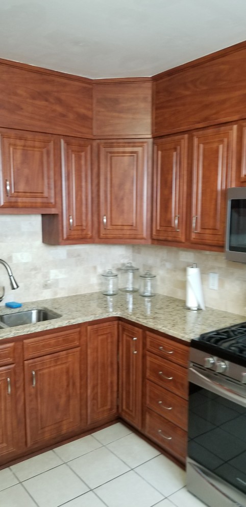 Exempel på ett mellanstort klassiskt beige beige kök, med en undermonterad diskho, luckor med infälld panel, röda skåp, granitbänkskiva, flerfärgad stänkskydd, stänkskydd i travertin, rostfria vitvaror, cementgolv och flerfärgat golv