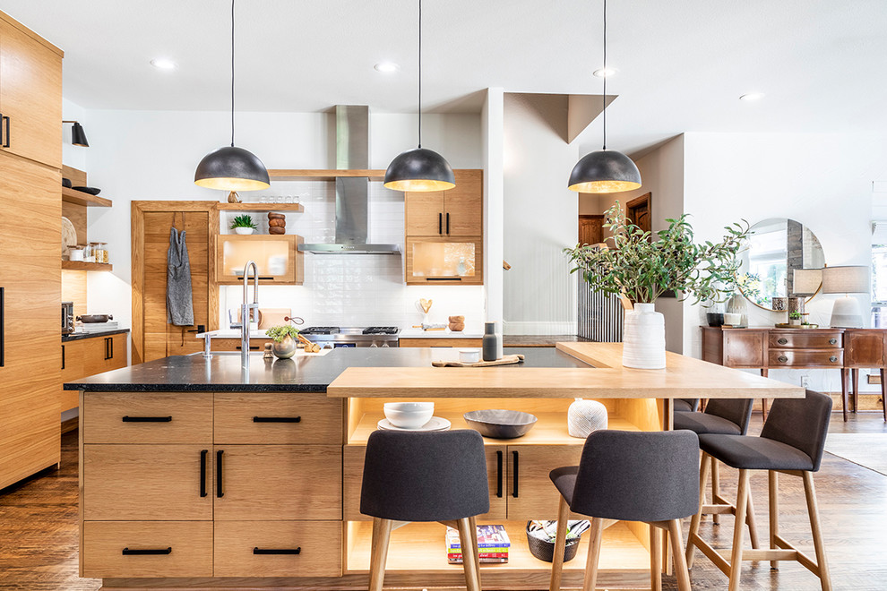 Свежая идея для дизайна: угловая кухня-гостиная в скандинавском стиле с светлыми деревянными фасадами, белым фартуком, техникой из нержавеющей стали, темным паркетным полом, островом и черной столешницей - отличное фото интерьера