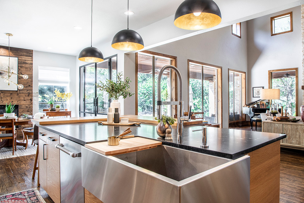 Photo of a scandi l-shaped open plan kitchen in Dallas with light wood cabinets, white splashback, stainless steel appliances, dark hardwood flooring, an island and black worktops.
