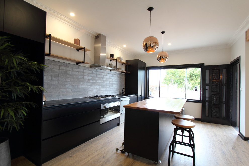Mid-sized urban single-wall laminate floor open concept kitchen photo in Melbourne with a single-bowl sink, open cabinets, black cabinets, laminate countertops, gray backsplash, subway tile backsplash, stainless steel appliances and an island