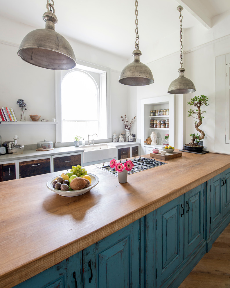 Photo of a large romantic open plan kitchen in Other with shaker cabinets, blue cabinets, wood worktops, stainless steel appliances, medium hardwood flooring, an island, brown floors, brown worktops and a belfast sink.