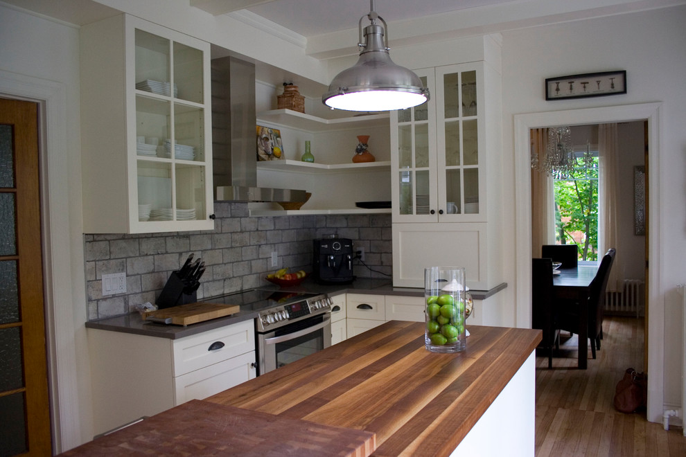 Klassisk inredning av ett mellanstort kök, med en nedsänkt diskho, skåp i shakerstil, vita skåp, träbänkskiva, grått stänkskydd, stänkskydd i cementkakel, rostfria vitvaror, en köksö och ljust trägolv