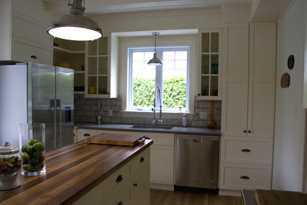 Klassisk inredning av ett mellanstort kök, med en nedsänkt diskho, skåp i shakerstil, vita skåp, bänkskiva i kvartsit, grått stänkskydd, stänkskydd i cementkakel, rostfria vitvaror, en köksö och ljust trägolv