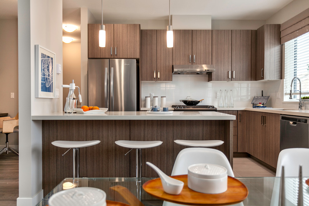 This is an example of a small contemporary l-shaped open plan kitchen in Vancouver with a submerged sink, flat-panel cabinets, medium wood cabinets, engineered stone countertops, white splashback, porcelain splashback, stainless steel appliances, porcelain flooring and an island.