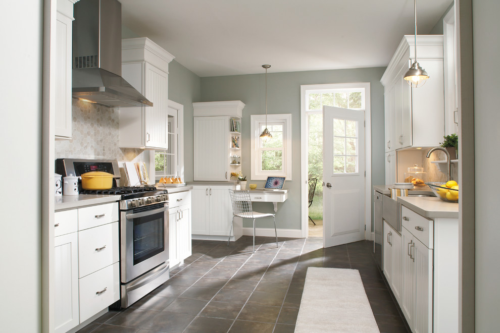 This is an example of a large traditional galley kitchen/diner in Indianapolis with a belfast sink, stainless steel appliances, beaded cabinets, white cabinets, engineered stone countertops, grey splashback, metro tiled splashback, ceramic flooring and a breakfast bar.