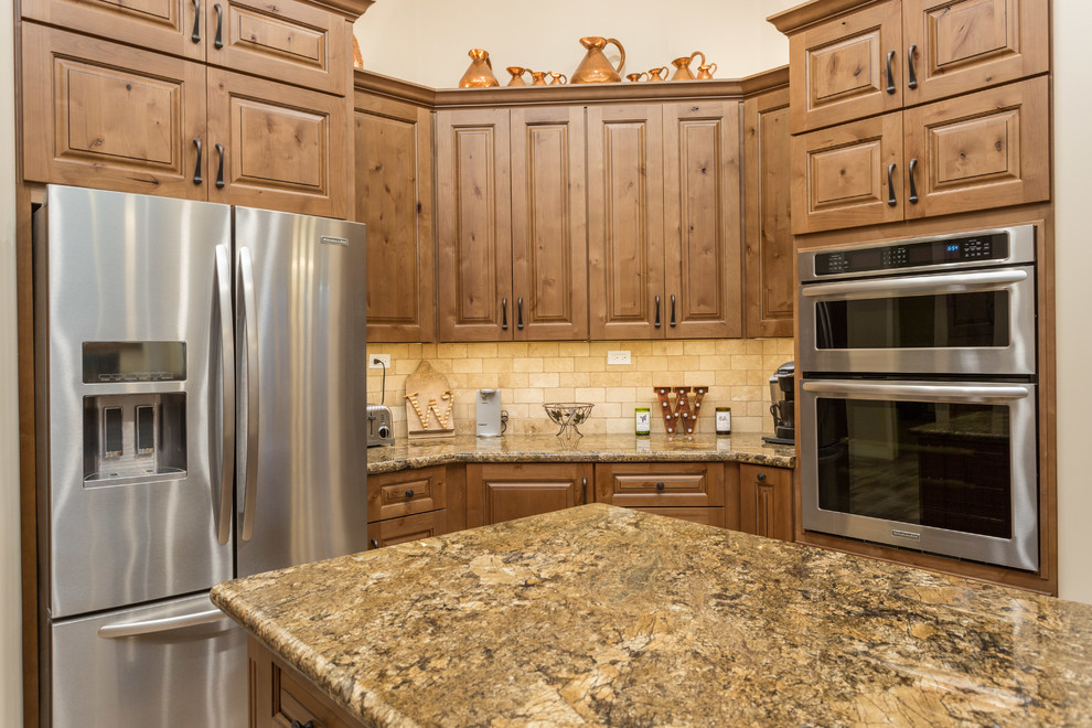 Foto på ett mellanstort rustikt kök, med en dubbel diskho, luckor med infälld panel, skåp i mellenmörkt trä, granitbänkskiva, beige stänkskydd, stänkskydd i terrakottakakel, rostfria vitvaror, klinkergolv i terrakotta och en köksö
