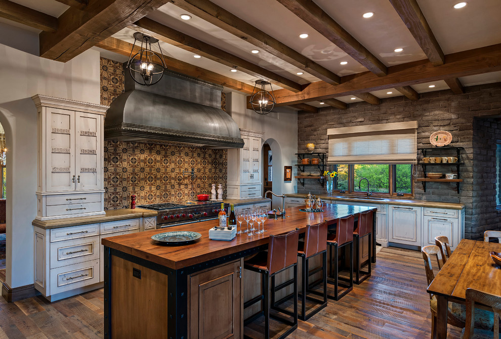 Southwest l-shaped dark wood floor kitchen photo in Phoenix with an undermount sink, raised-panel cabinets, white cabinets, brown backsplash, stainless steel appliances and an island