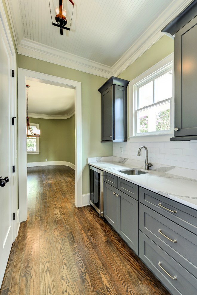 Enclosed kitchen - mid-sized transitional single-wall medium tone wood floor and brown floor enclosed kitchen idea in Atlanta with a farmhouse sink, shaker cabinets, gray cabinets, marble countertops, white backsplash, subway tile backsplash, stainless steel appliances and an island
