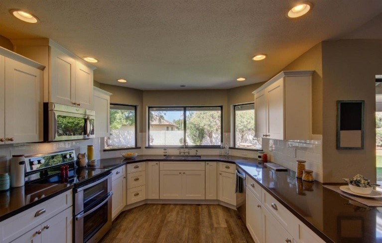 Eat-in kitchen - mid-sized contemporary u-shaped porcelain tile eat-in kitchen idea in Phoenix with an undermount sink, shaker cabinets, white cabinets, quartzite countertops, white backsplash, subway tile backsplash, stainless steel appliances and no island