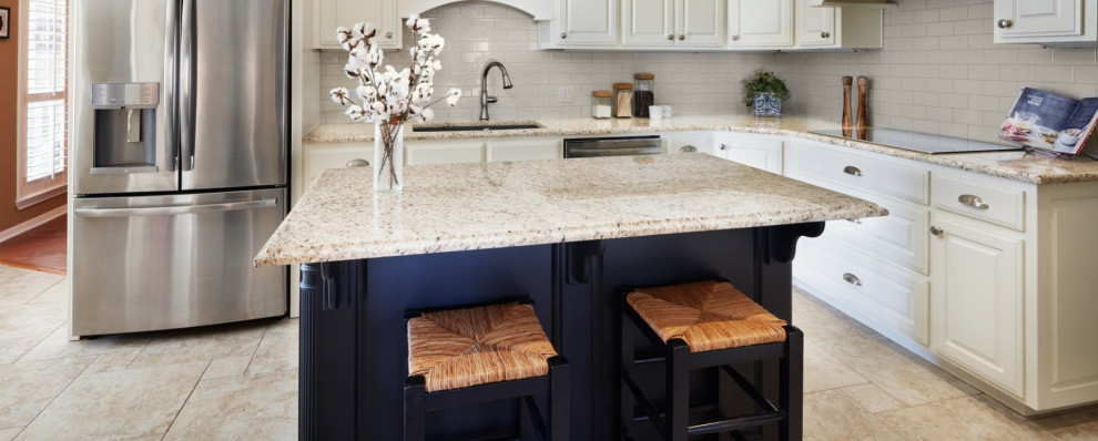 Klassisk inredning av ett mellanstort svart svart kök, med en undermonterad diskho, luckor med upphöjd panel, vita skåp, granitbänkskiva, vitt stänkskydd, stänkskydd i keramik, rostfria vitvaror, klinkergolv i porslin, en köksö och beiget golv