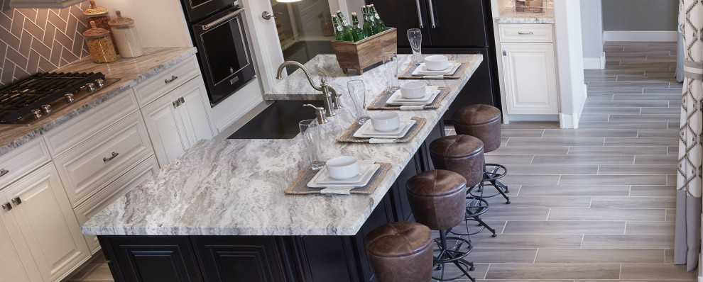 Exempel på ett mellanstort klassiskt grå grått kök, med en rustik diskho, luckor med upphöjd panel, vita skåp, marmorbänkskiva, beige stänkskydd, stänkskydd i glaskakel, svarta vitvaror, klinkergolv i porslin, en köksö och beiget golv