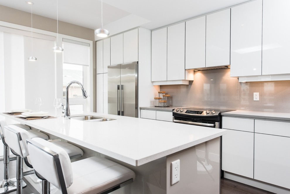 Photo of a medium sized modern grey and white single-wall kitchen/diner in Toronto with a submerged sink, flat-panel cabinets, white cabinets, grey splashback, glass sheet splashback, stainless steel appliances, an island, quartz worktops and dark hardwood flooring.
