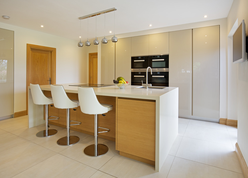 Large contemporary single-wall kitchen/diner in London with a submerged sink, flat-panel cabinets, beige cabinets, composite countertops, stainless steel appliances, ceramic flooring, an island and white floors.