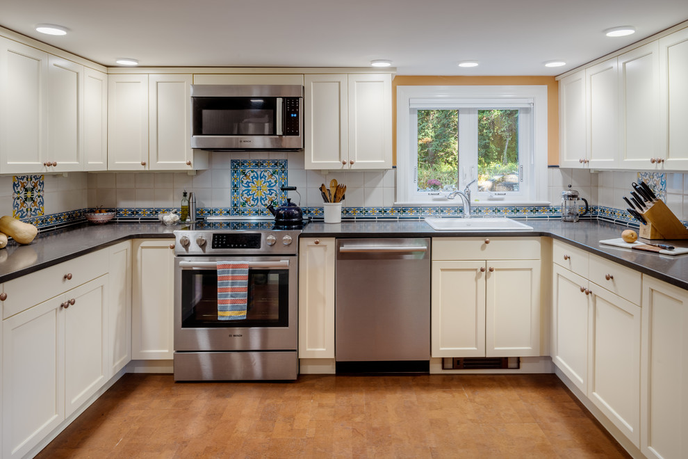 Elegant u-shaped cork floor and brown floor kitchen photo in Boston with a drop-in sink, shaker cabinets, soapstone countertops, multicolored backsplash, ceramic backsplash, stainless steel appliances, no island, black countertops and beige cabinets