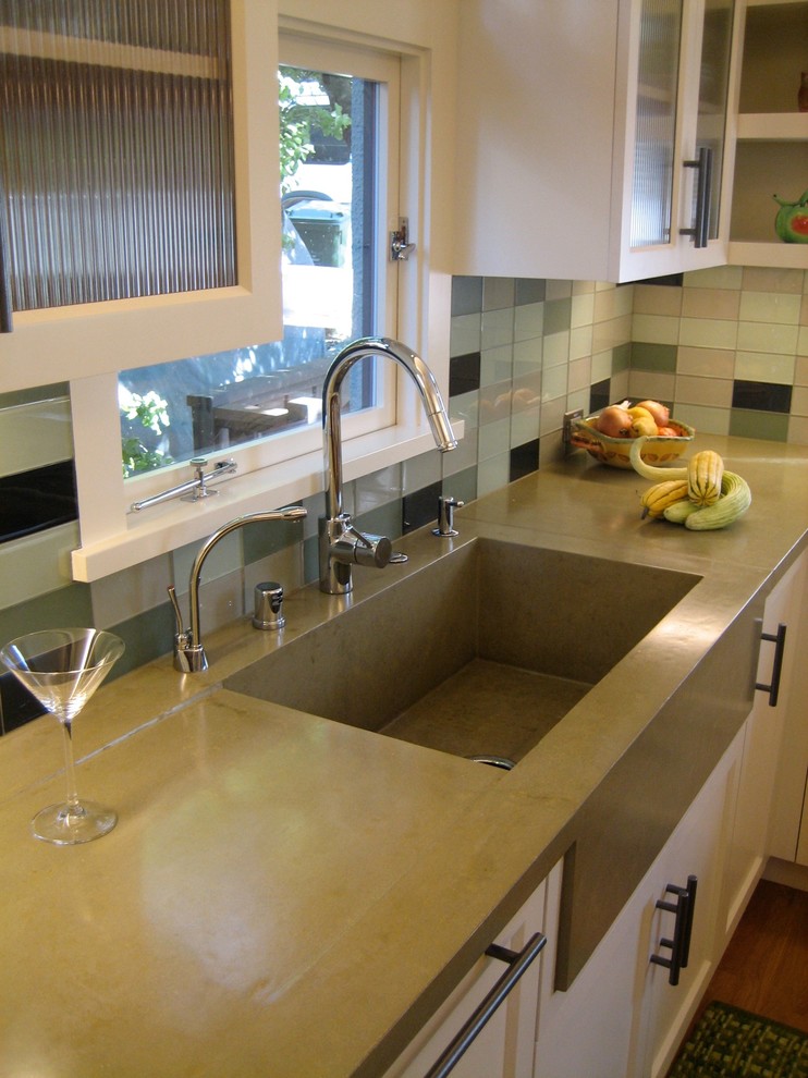 Foto på ett mellanstort funkis kök, med luckor med infälld panel, vita skåp, bänkskiva i betong, stänkskydd i glaskakel, rostfria vitvaror, mellanmörkt trägolv, en köksö och en integrerad diskho