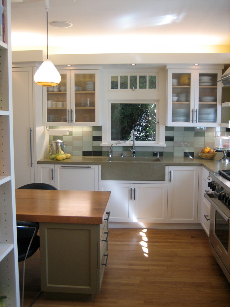 Idéer för ett mellanstort modernt kök, med en enkel diskho, luckor med infälld panel, vita skåp, bänkskiva i betong, stänkskydd i glaskakel, rostfria vitvaror, mellanmörkt trägolv och en köksö