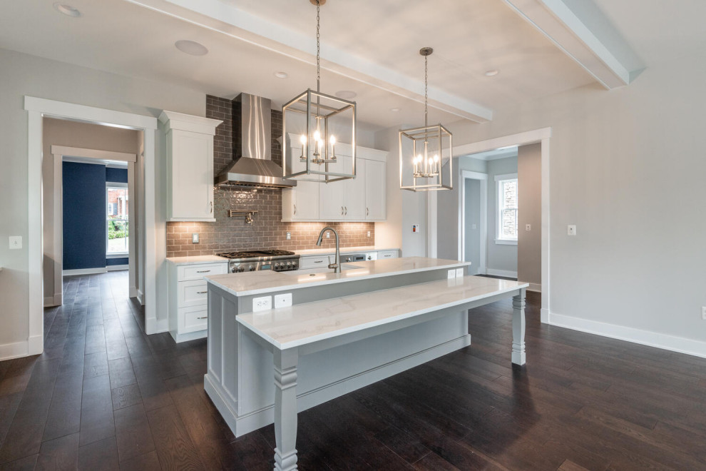 Inspiration for a medium sized classic l-shaped open plan kitchen in DC Metro with a belfast sink, shaker cabinets, grey cabinets, engineered stone countertops, grey splashback, ceramic splashback, integrated appliances, dark hardwood flooring, an island, brown floors, white worktops and exposed beams.