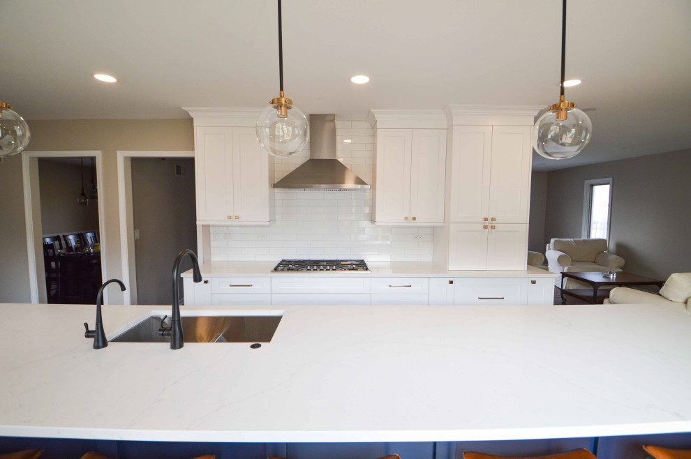 Inspiration for a large traditional kitchen/diner in Chicago with white cabinets, engineered stone countertops, white splashback, stainless steel appliances, medium hardwood flooring, an island and white worktops.