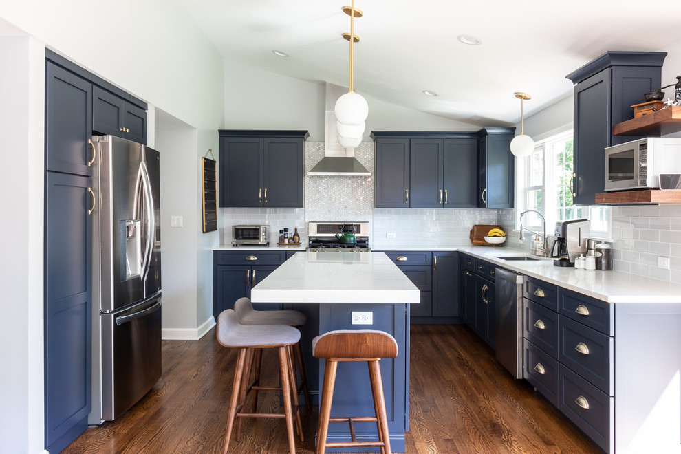 Inspiration for a transitional l-shaped dark wood floor and brown floor eat-in kitchen remodel in Boston with an undermount sink, shaker cabinets, blue cabinets, quartz countertops, blue backsplash, glass tile backsplash, stainless steel appliances, an island and white countertops