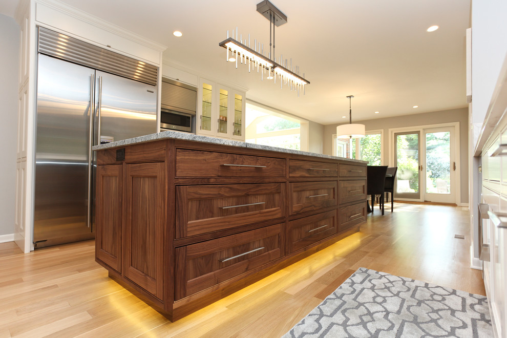 Large contemporary u-shaped open plan kitchen in Chicago with a submerged sink, flat-panel cabinets, medium wood cabinets, grey splashback, stone tiled splashback, stainless steel appliances, an island, light hardwood flooring and marble worktops.