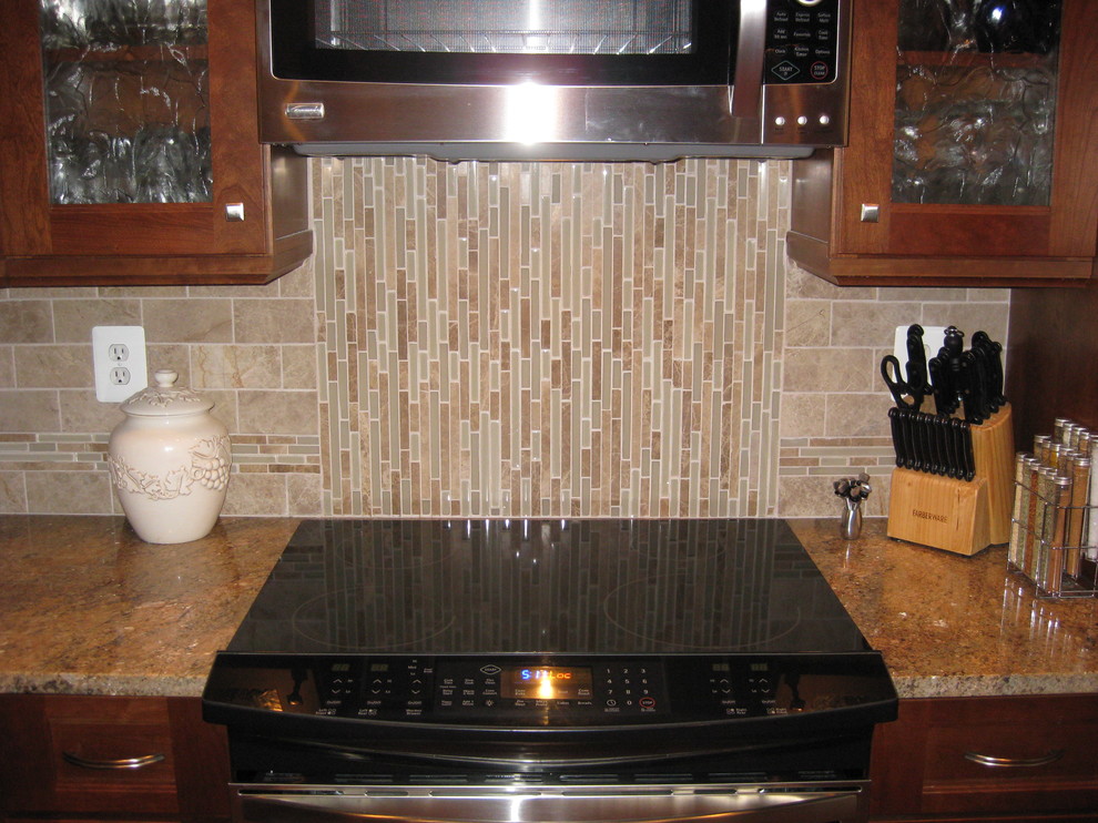 Immagine di una cucina a L tradizionale con lavello sottopiano, ante lisce, ante in legno scuro, paraspruzzi beige e paraspruzzi con piastrelle in pietra